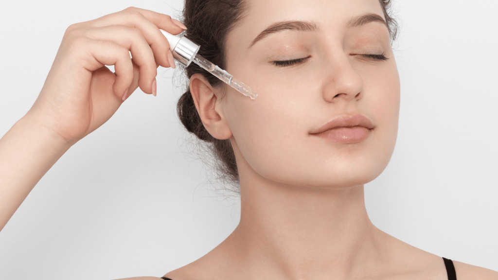 Primer plano de una mujer echándose en la cara un sérum con cuentagotas